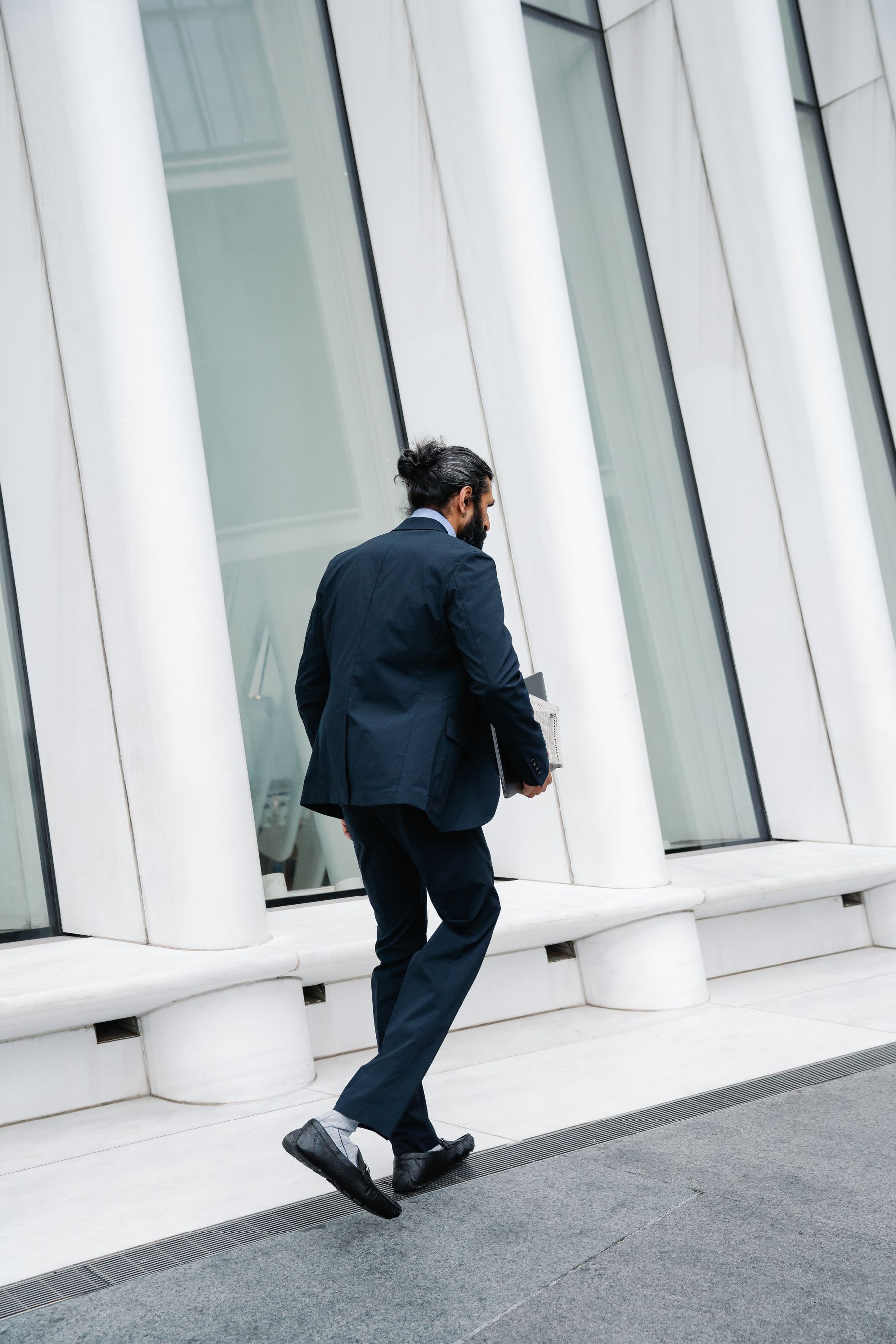 A professional walking alongside a pale modern facade