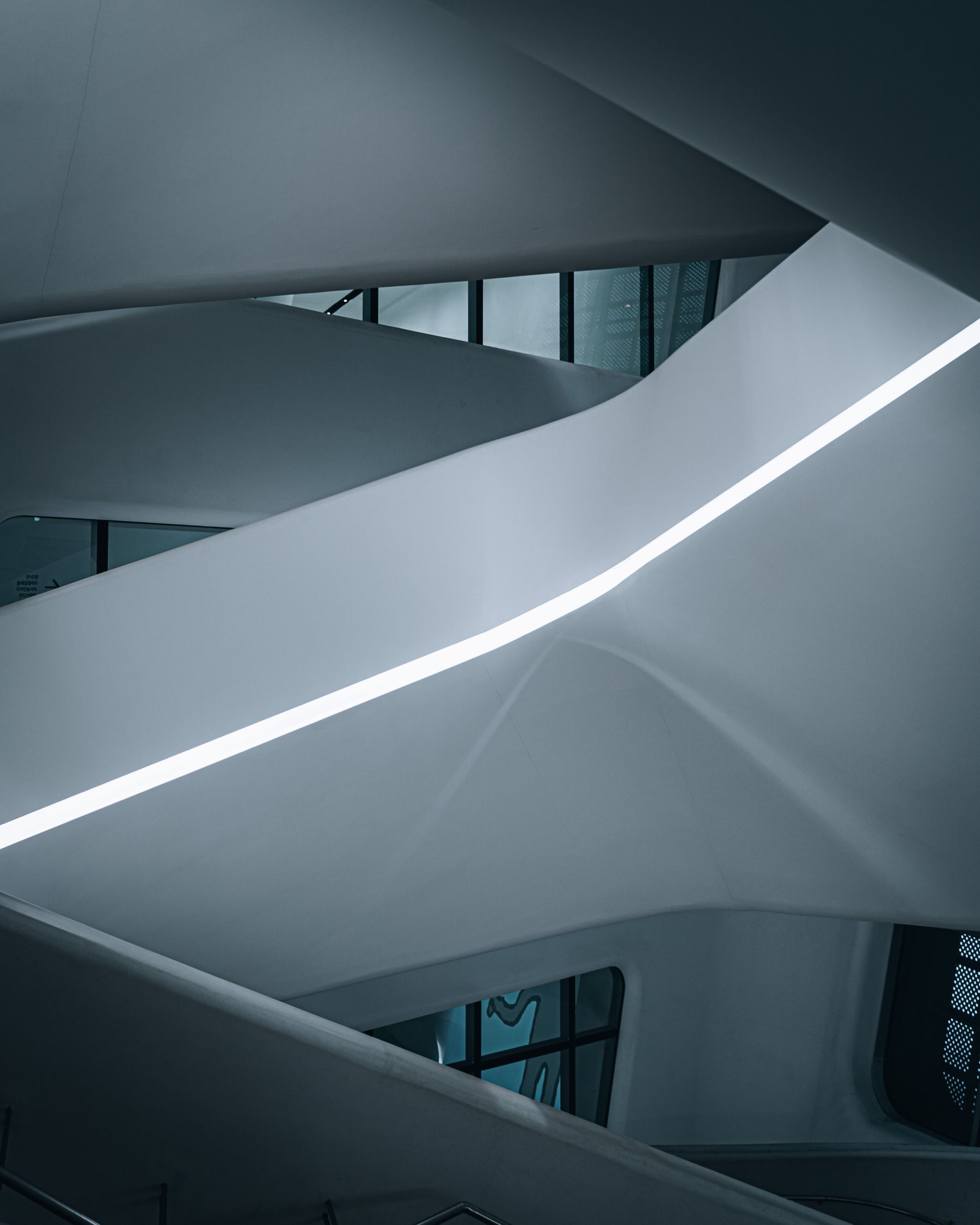 A sculptural staircase with curved white walls and a narrow band of light